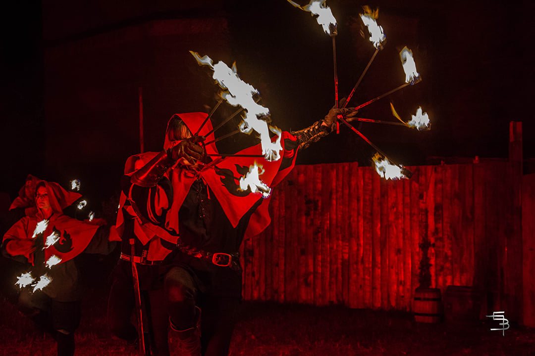 Encapuchonnés de rouge maniant des éventails de feu