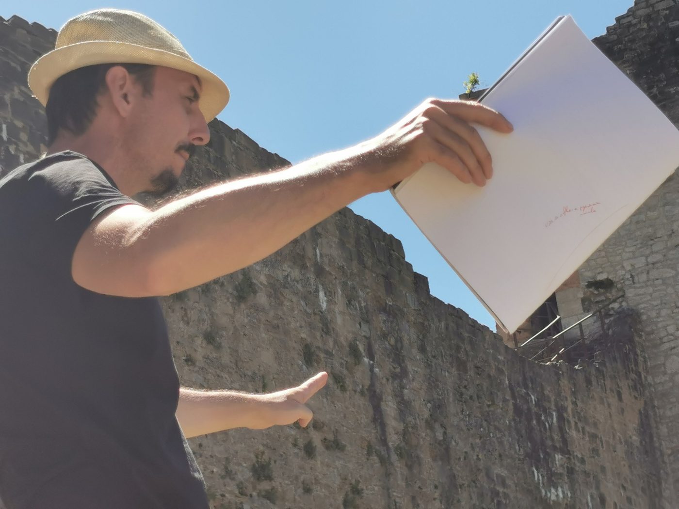 Gaël Dubreuil, chapeau de paille, texte à la main, donne une indication devant une muraille de château